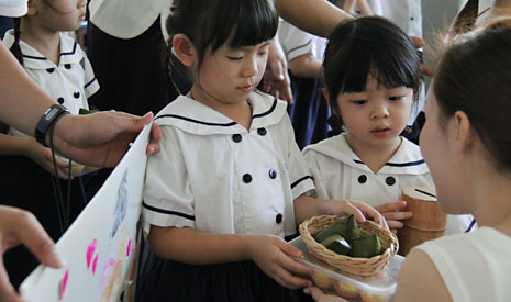 孩子們手拿一盤粽子和一盒薯泥塔，誠懇地向家長募心募款。【攝影者：楊瑋欣】