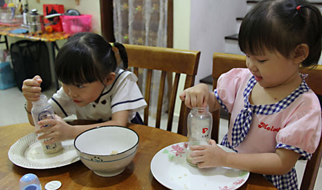 一粒一粒放入奶瓶裡的米，滴水成河，可見孩子的善心在發芽。（左：莊禾靖、右：莊禾群）【攝影者：莊濟智】