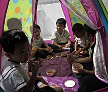 在炎熱的天氣下，小朋友還得坐在擁擠的帳篷內一起用餐，大家都感到受不了。【攝影者：陳潔瑩】