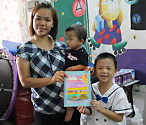 黃銘宇小朋友（右）代表大慈班將大家自制的繪本贈送給特殊儿童中心的負責人詹素萍（左）。【攝影者：胡慧芬】