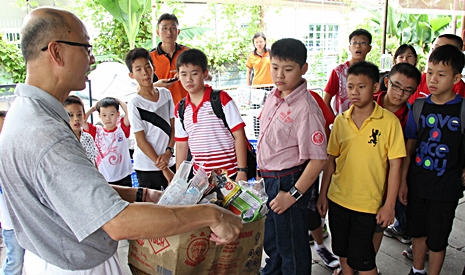 慈濟志工蕭益光（左一）向學生解釋如何分類眼前這一箱的回收物。【攝影者：胡慧芬】