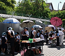 頂著太太陽，男人撐著雨傘不怕日曬，替在露天廚房烹飪的女人與孩子遮陽， 場面如此溫馨。【攝影者：莊鞳勛】