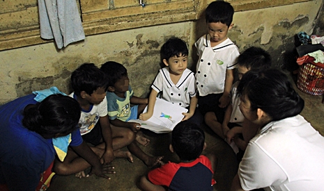 慈濟幼兒園小朋友席地而坐，為照顧戶的孩子們講故事。【攝影者：胡慧芬】