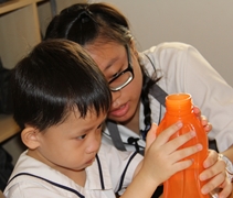 陳慧盈老師指導著小朋友喝水的份量。【攝影者：許春龍】