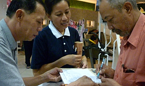 慈濟志工潘思伻（慈渶）與簡永學在購物中心內向一名馬來民眾募心募款。【攝影者：林秋芬】