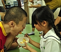 北海慈濟幼兒園的孩子在老師們的牽引下，喂糕點給身心障礙者吃。【攝影者：龔美麗】