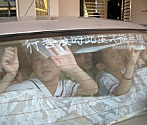 慈濟幼兒園小朋友正用心地幫忙鄰居把靜思語貼在車鏡上。【攝影者：陳曉俐】