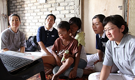 慈濟志工（左起）王麗萍、左玉花（慈侔）、黃麗珠（慈沇）和黃麗端，陪同照顧戶達娜姆和她的小兒子，觀看泰語版泰國大藏經影片。【攝影者：顏如艷】