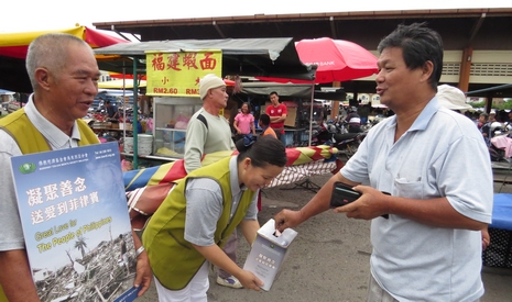 早晨的菜市場，慈濟志工分別拿著募心募款說明看板和募心箱，鞠躬感恩民眾的愛心付出。【攝影者：馬耀甄（慈甄）】