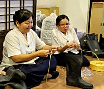 靜思堂同仁將一對對同樣型號的雨鞋，用繩子捆綁進來，以方便使用。左一起為：柯翠玲（慈琁）和梁秀芬（慈康）。【攝影者：胡慧芬】