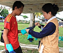 慈濟志工陳馨波（慈馨）（右）為前來帮忙的受災鄉親，戴上手套。【攝影者：胡慧芬】