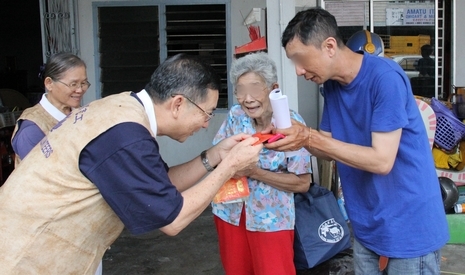 慈濟志工為年屆八十的受災戶黃秀金和她的兒子李仕慶鞠躬獻上慰問金，他們身後的藍色袋子則是志工與之發放的物資。【攝影者：顏如艷】