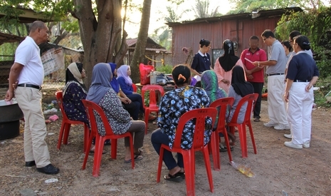 送來物資和慰問金的慈濟志工，為受災戶莫哈末羅茲（Mohd Rozi bin Ishak）和他的妻子恭讀證嚴法師給災民的慰問信，親友們也在一旁聆聽。【攝影者：顏如艷】