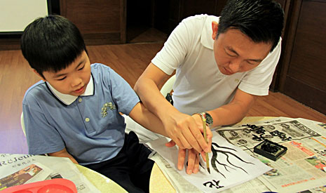 握著孩子的手，眼前這位爸爸教導孩子如何寫書法，親子之間變得更為親密。【攝影者：胡慧芬】