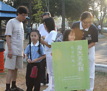 兩位小菩薩雖不會勸募，知道是在做好事，一早跟著母親到公園幫忙，一臉笑意，感染著周邊許多善心人。【攝影者：張燕茹】