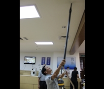 志工吳育才正在使用吸塵機清理天花板。【攝影者：顏如艷】