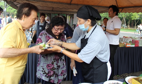 慈濟志工郭賢清讓民眾試吃各式各樣美味的素食料理。【攝影者：魏嘉妍】