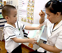 慈濟幼兒園老師朱施穎（慮昉）（右）引導四歲孩子如何愛護繪本。【攝影者：胡慧芬】