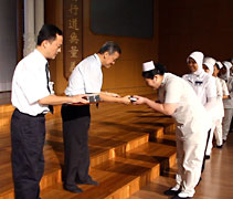 馬來西亞分會執行長郭濟緣（左二）分發結緣品給每一位同仁。【攝影者：胡慧芬】