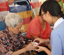 慈少同學葉心慧為安養中心裡的阿嬤奉上一杯茶。【攝影者：呂寶晶】