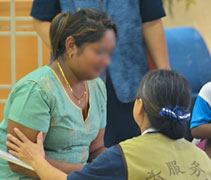 陪伴瑪伽的訪視志工賴玉嫻（慮茹）蹲低身子，膚慰瑪伽的女兒葛麗（Gaury Mami Vello）。【攝影者：劉玲妹】