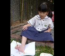 黃柔瑄小朋友用腳指夾住水彩筆，嘗試體會沒有雙手的難處。參訪殘障職訓中心後，她覺得自己很幸福：「因為我們有健全的身體。」【攝影者：劉欣艷】