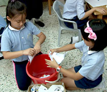 孩子們把撕碎的紙張，先丟進桶裡，准備制作再生紙。【攝影者：胡慧芬】