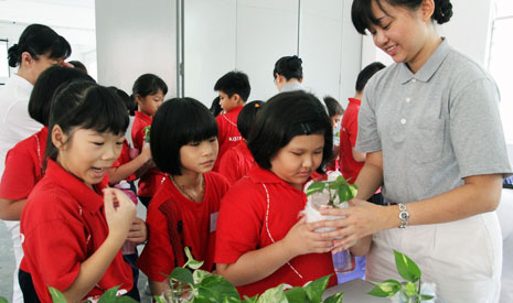 陳依寧師姊把生活組準備好的環保花盆和萬年青交個同學們。【攝影者：楊雯元】