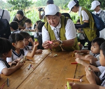 大愛媽媽王小貞向小朋友們示範如何把捲成圓錐形的顏色紙卡粘起來。【攝影者：翟佩庭】