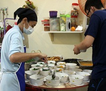 結束掉神料祭品的檔口生意，林秫屹（慈穰）轉在家裡煮素食供應外包，一樣從事素食工作的兒子成了好幫手。【攝影者：陳韻如】