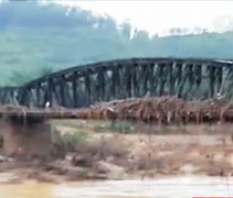 這座近百年歷史的大橋，因豪雨引發河水水位高漲，一度淹沒河上橋梁。枯木和漂流物阻礙了村民與外界的交通。【畫面截取自大愛新聞】