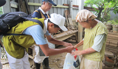 慈濟志工到一位八十高齡災民的家發放，慈少恭敬地將物資送上。【攝影者：文玉芳】