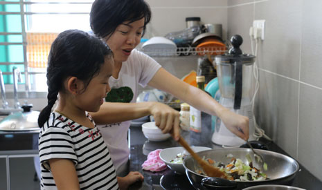 鍾姃穎跟在媽媽身邊學做菜，偶爾也會試著拿起鍋鏟炒菜。【攝影者：翟佩庭】