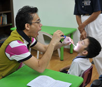 耳鼻喉科醫師黃健洋請曾靖衡小朋友張開嘴巴，讓他檢查口腔。【攝影者：黃玉龍（濟祧）】