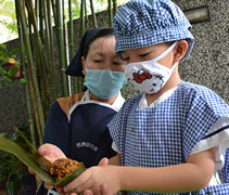 在新山慈濟幼兒園，大愛媽媽陳碧芸（慈苗）教導曾靖衡小朋友包粽子。【攝影者：戴佳玉（慈迪）】