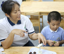 幼兒園杜旭絲老師教導小朋友們親自動手捏餅皮，放紅豆餡，然後用模型壓出一個小月餅，做為他們飯後的小點心。【攝影者：邢薇薇】