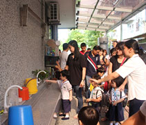 老師們以攻站的方式讓新生和家長認識幼兒園的環境。多功能有蓋走廊，設有配合孩子高度的洗手盆；這裡也設立洗碗區，讓五歲和六歲的小朋友在用過午餐後，學習清洗自己的環保碗。【攝影者：翟佩庭】