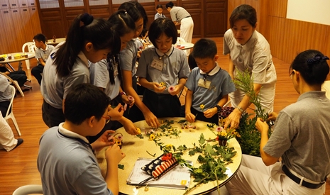 教育志工正在指導孩子們如何利用花花草草製作成小花籃。【攝影者：陳國榮】