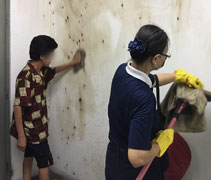 慈濟志工帶著駱婆婆的女兒一同清洗牆壁上的污跡，把跳蚤的污跡洗刷掉。【攝影者：莊慈聆】