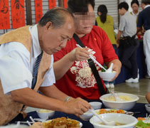 志工們準備了四菜一湯，並陪伴大家提前享用團圓飯，慈濟志工蔡欣江（濟慶，左）貼心地為照顧戶盛湯。【攝影者：梁遠文（濟平）】