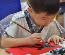 四歲班的李藝滜小朋友非常專注地寫春聯。【攝影者：劉曉秀】