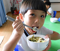 六歲班的陳俊宇正開心地享用著自己和同學們一起準備的素湯麵，四歲及五歲的弟弟妹妹們也有口福。【攝影者：翟佩庭】