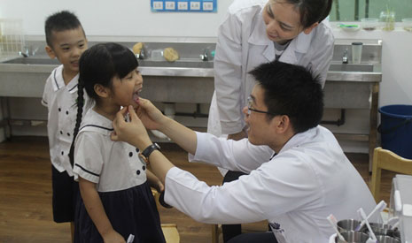 牙醫細心檢查小朋友刷牙後的牙齒，親切的舉動讓孩子不再害怕身穿白袍的醫師。【攝影者：許瑋師】