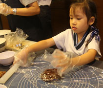 峇六拜幼兒園學生羅靖善在大愛媽媽的陪伴下用靜思食品製作小餅乾，供出席者食用。【攝影者：黃翊晴】