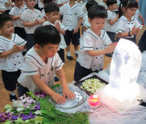 黃丞熙小朋友（前左）誠心地雙手合掌，然後恭敬地沾香湯「禮佛足」。【攝影者：翟佩庭】