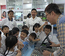 北海眼鏡店的老闆給到來參訪的北海慈濟幼兒園學生和老師們介紹眼鏡並進行講解。【攝影者：洪繪萍】