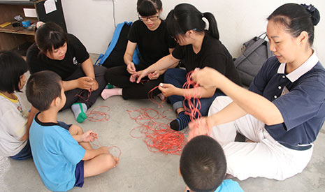 台東大學幼教系學生通過慈濟志工，得知案主家的生活背景後，便準備了簡易的材料，與小朋友一同製作長繩，用於玩遊戲。【攝影者：邱佩軒】