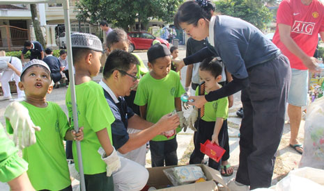 慈濟志工陳登科（惟登，左）和黃麗玲（慈昀，右）教導孩子們認識可回收資源。【攝影者：劉玉容（慮化）】