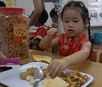 檳城慈濟幼兒園小朋友把用於招待弟弟妹妹的蘆柑及新年糕餅擺在餐盤上。【攝影者：黃翊晴】