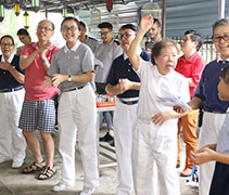 慈濟師兄師姊人人臉上都掛著大大的笑容，歡喜唱歌、表演，感染現場的長者。要求鏡中人笑，自己要先笑。【攝影者：邢薇薇】